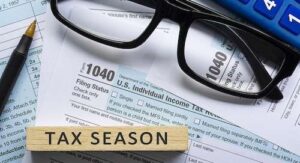 Tax season text on wooden block with Tax forms 1040. U.S Individual Income Tax