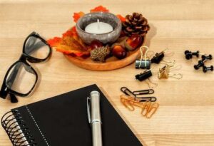Spiral notepad with a pen, supplies and autumn leaves