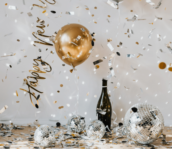 Happy New Year celebration, gold balloons, disco balls, confetti, champagne